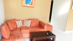 A living room with a sectional sofa, patterned cushions, a wooden coffee table, and a framed abstract painting on the wall. - fresh apartment 90 m2,  with huge balcony (Bávaro)