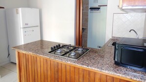A compact kitchen with a built-in gas stove, a microwave, and a refrigerator. - fresh apartment 90 m2,  with huge balcony (Bávaro)