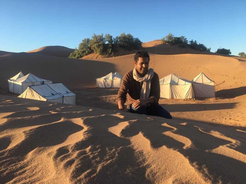 A desert landscape with tents and sand dunes.