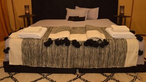Un lit bien fait, avec une couverture à rayures et des motifs floraux noirs, deux tables de chevet et un tapis à motifs.
