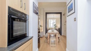 A kitchen with a black oven, wooden cabinets, and a dining area with a wooden table and benches.