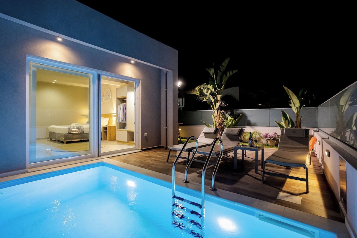 Un espace piscine extérieur moderne, doté d’une porte vitrée donnant accès à une chambre, d’un fauteuil de relaxation et d’une petite table avec un ventilateur.