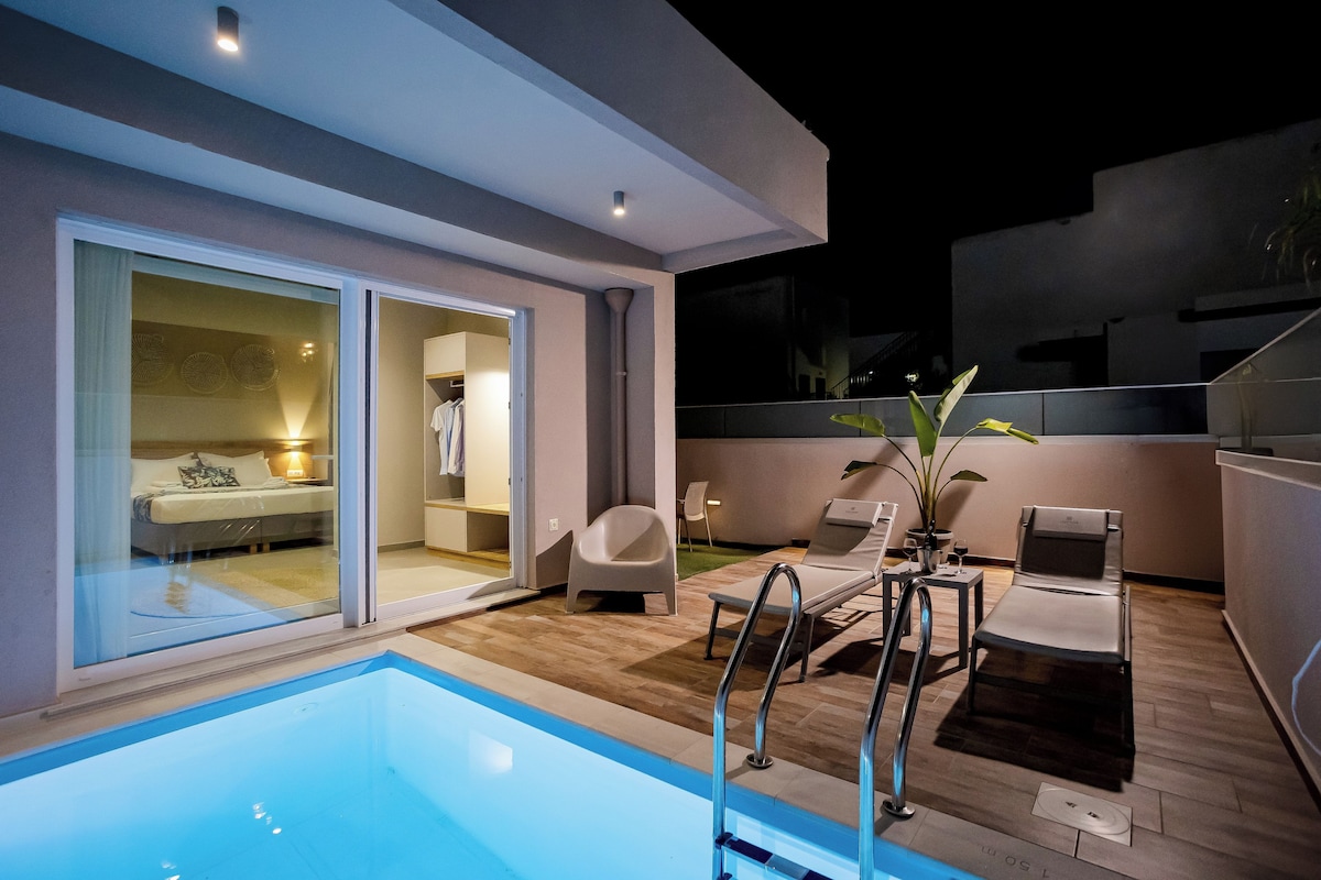 Un espace piscine extérieur moderne, doté d’une pièce fermée par des baies vitrées, d’une chaise longue et d’une petite table.