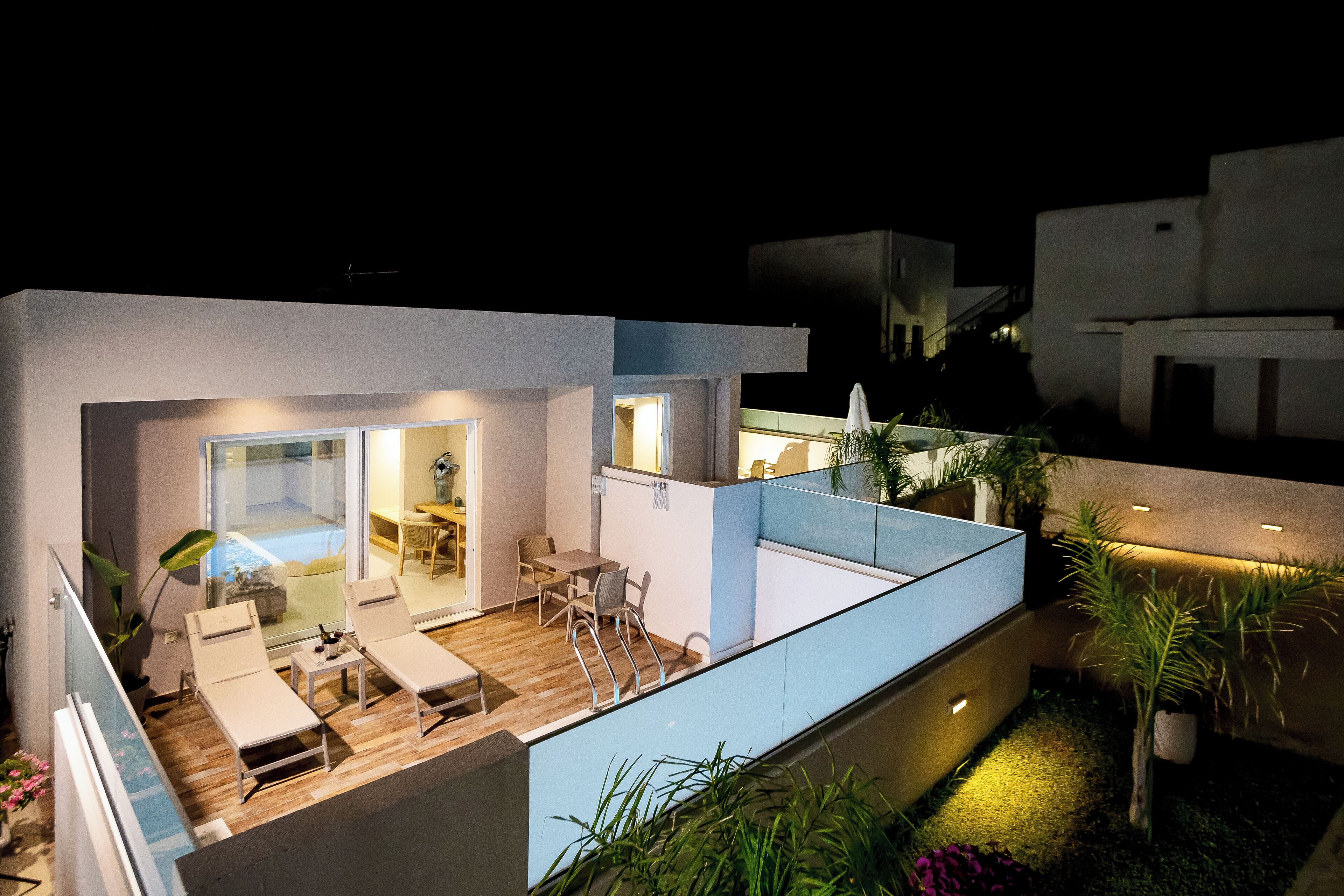 Un espacio exterior moderno con piscina, sillas de descanso y una mesa de comedor.