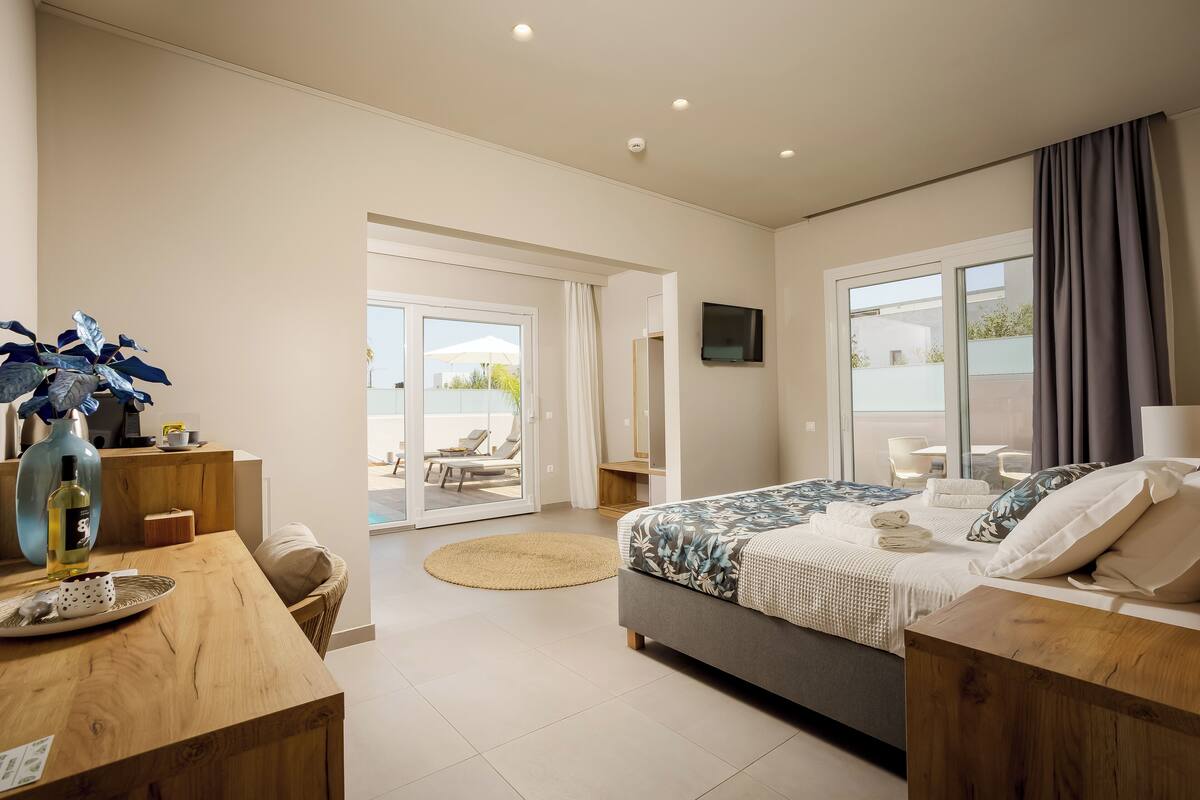 Una habitación de hotel moderna con una cama grande, un escritorio, una silla y vistas al área exterior.