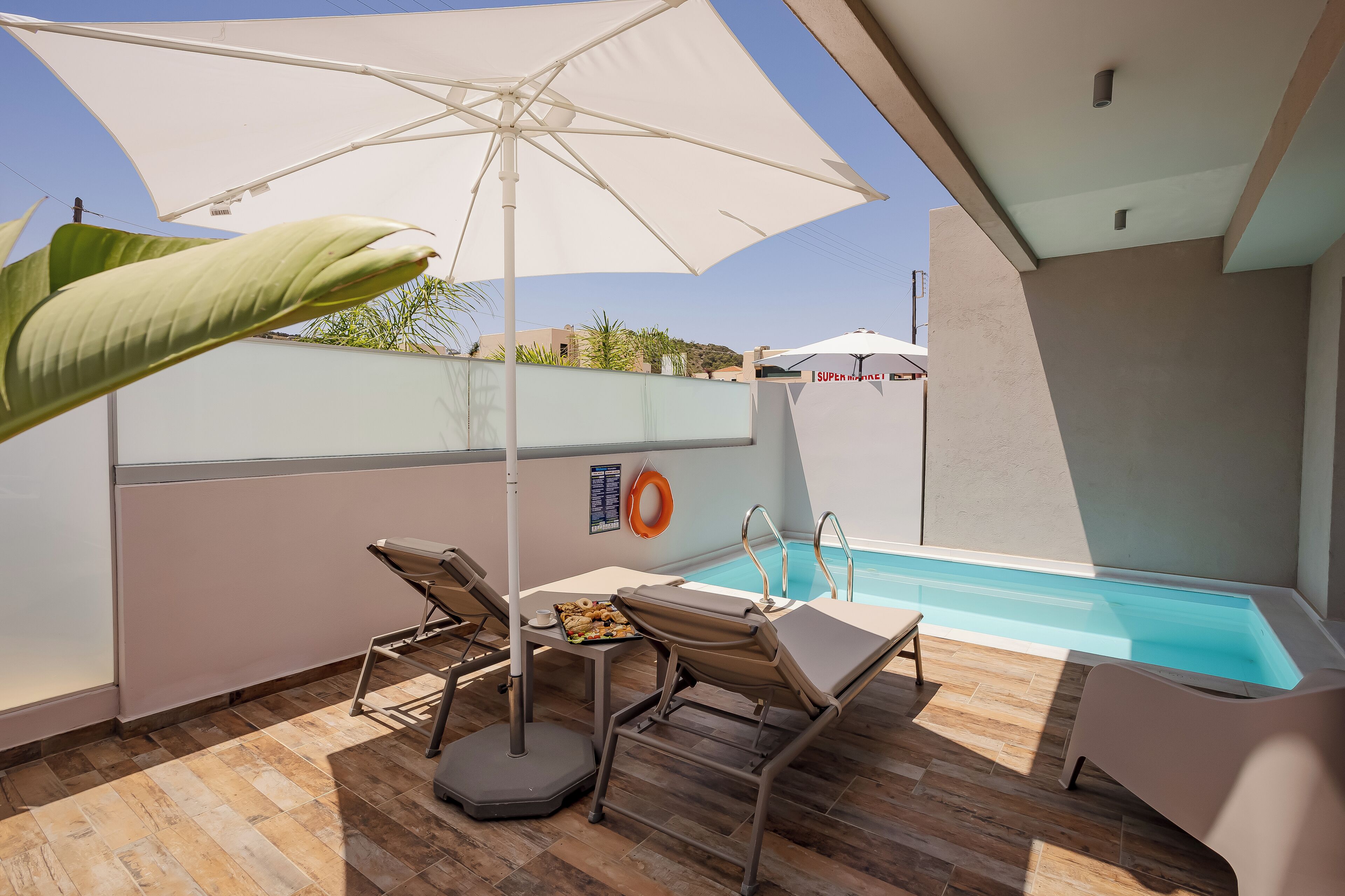 A rooftop pool area with lounge chairs, an umbrella, and a lifebuoy.