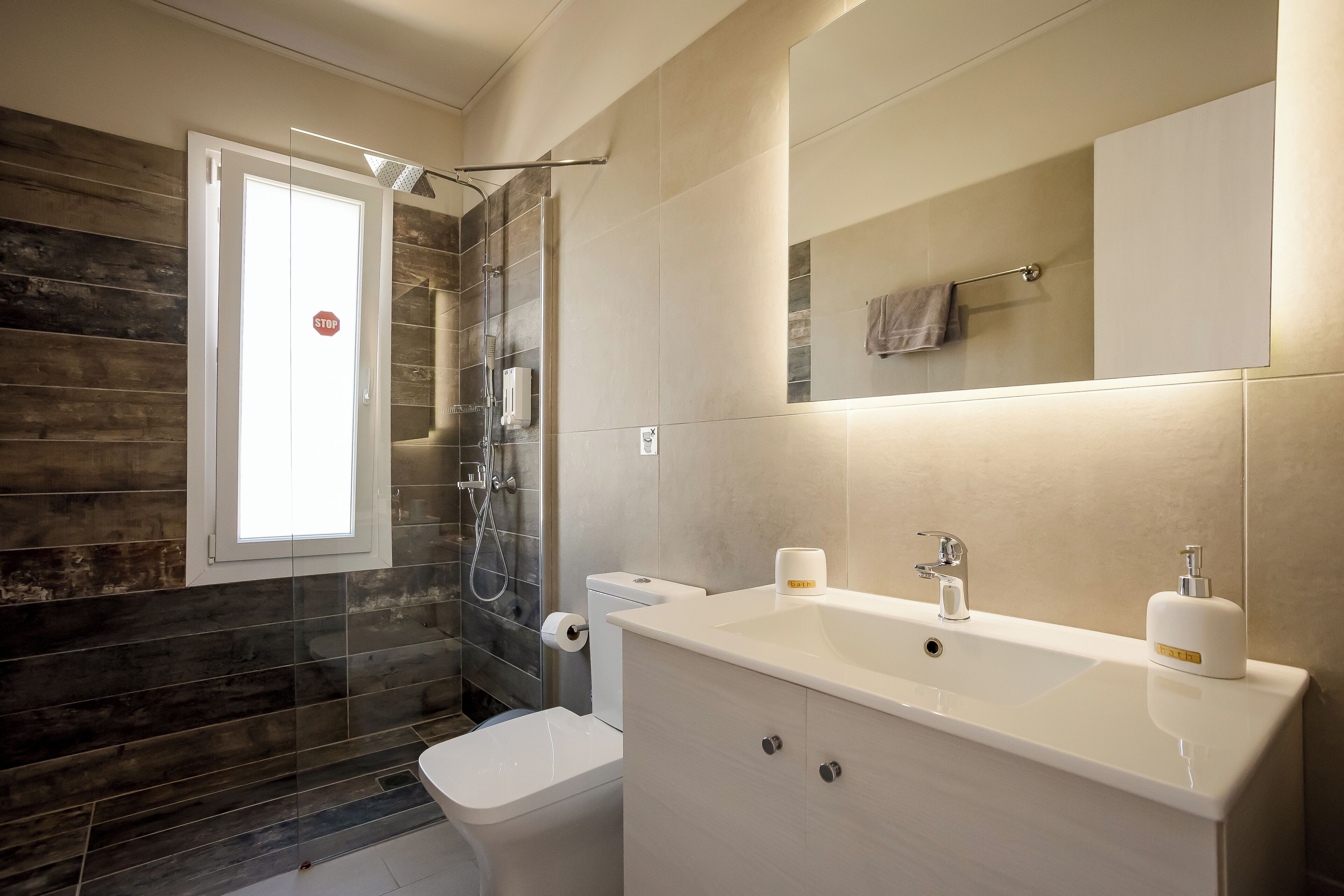 A modern bathroom with a glass shower enclosure, a toilet, a sink with a mirror, and a towel rack.