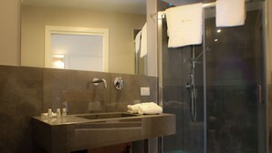 A modern bathroom with a large mirror, a sink with a towel, and a glass-enclosed shower. - Be Italian Room Bovio 23 (Naples)