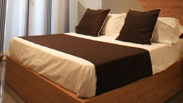 A modern bedroom with a large bed, a wooden headboard, and a large window with sheer curtains. - Be Italian Room Bovio 23 (Naples)