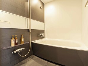 Une salle de bain moderne équipée d’une baignoire, d’une douche et d’un sèche-mains.