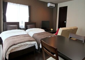 Two single beds with matching headboards and footboards, a small table, and a chair create a functional space.