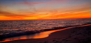 Ein Strand mit Wellen und einem Sonnenuntergang.
