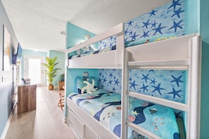 A bunk bed room with a star-patterned bedspread, a potted plant, and a wooden desk. - 120 steps to QUIET beach -PCB Hidden Gem- Clean. Full Kitchen. Hot Tub Mini Golf (Panama City Beach)