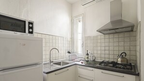 Una cocina compacta con microondas, estufa, lavamanos y ventana.