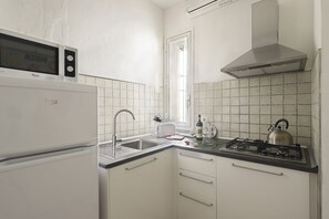 A compact kitchen with a microwave, stove, sink, and a window.