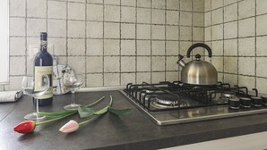 Una cocina con estufa a gas, una botella de vino, dos copas de vino y tulipanes sobre la encimera.