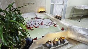 A bathtub with rose petals, candles, and a potted plant in a spa-like setting. - Loft Hotel Ipiales (Ipiales)