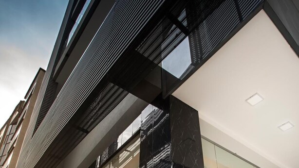 A modern building with a glass facade, large windows, and a black marble entrance. - Loft Hotel Ipiales (Ipiales)