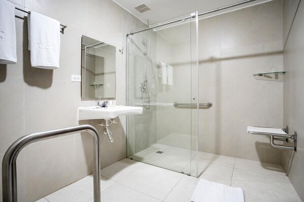 Un baño moderno con ducha de vidrio, lavamanos y espejo.