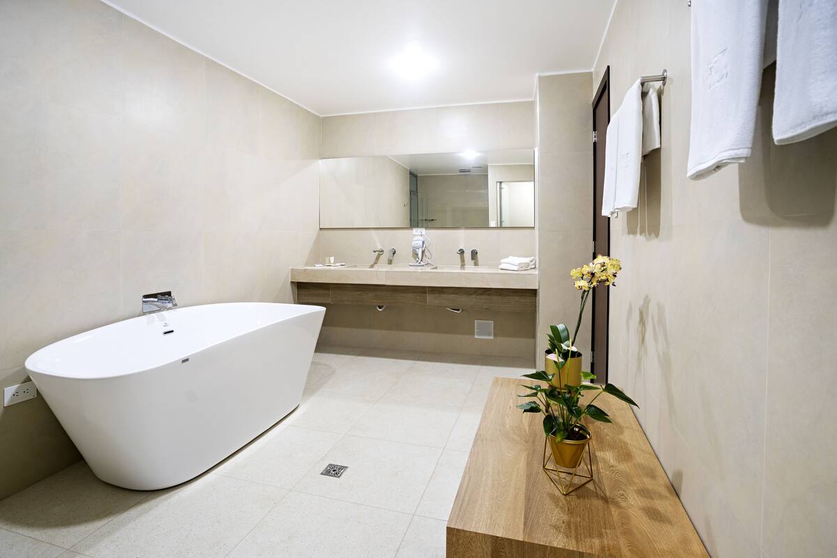 A modern bathroom with a freestanding bathtub, a wooden vanity, and a mirror above the sink.
