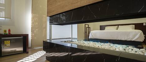 A modern hotel room with a bed, a wooden ceiling, and a marble countertop with a pebble tray.