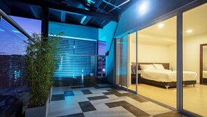 A modern bedroom with a large bed, a sliding glass door to a balcony, and a checkered floor. - Loft Hotel Ipiales (Ipiales)