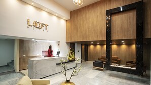 A modern hotel lobby with a reception desk, seating area, and a large mirror. - Loft Hotel Ipiales (Ipiales)