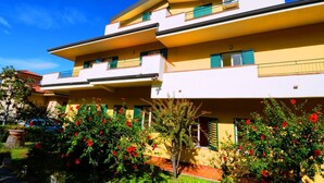A two-story building with balconies and a garden with red flowers. - Sole apartment with sea view and free wi fi (n ° 3) (Santa Domenica)