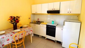 A compact kitchen with white cabinets, a black stove, and a white refrigerator. - Sole apartment with sea view and free wi fi (n ° 3) (Santa Domenica)