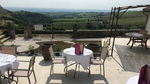 Eine Außenpatio mit runden Tischen und Stühlen, Blick auf die Landschaft und einer Pergola.