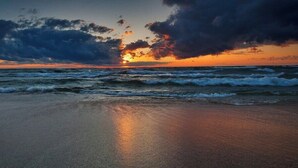 Ein Strand mit Wellen und einem Sonnenuntergang.