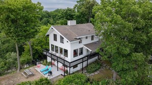 Ein zweistöckiges Haus mit einer großen Terrasse und einem Swimmingpool.