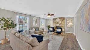 A living room with a sofa, chairs, a fireplace, and a ceiling fan.