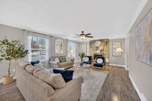 Un salon comprenant un canapé, des fauteuils, une cheminée et un ventilateur de plafond.