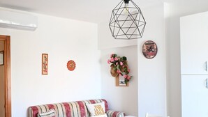 A dining area with a white table and chairs, a striped sofa, and a geometric pendant light. - M033 - Marcelli, three-room apartment in the center facing the sea (Marcelli)