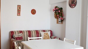 A room with a white table, a striped sofa, and a wall clock. - M033 - Marcelli, three-room apartment in the center facing the sea (Marcelli)
