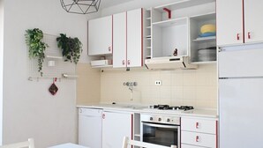 A kitchen with white cabinets, a gas stove, a dishwasher, and a refrigerator. - M033 - Marcelli, three-room apartment in the center facing the sea (Marcelli)