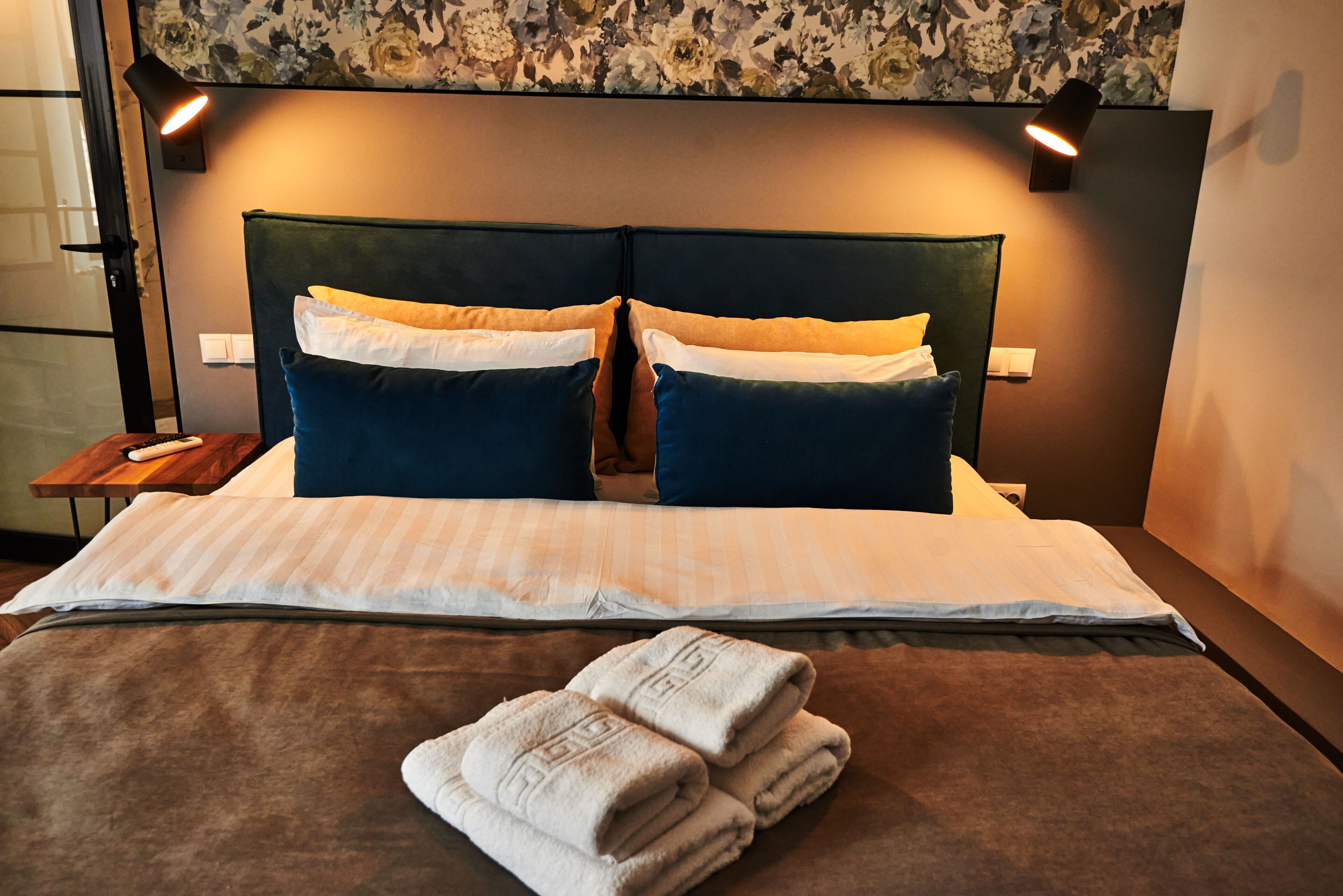Una cama bien hecha con una colcha a rayas, dos almohadas y una toalla doblada sobre la cama.