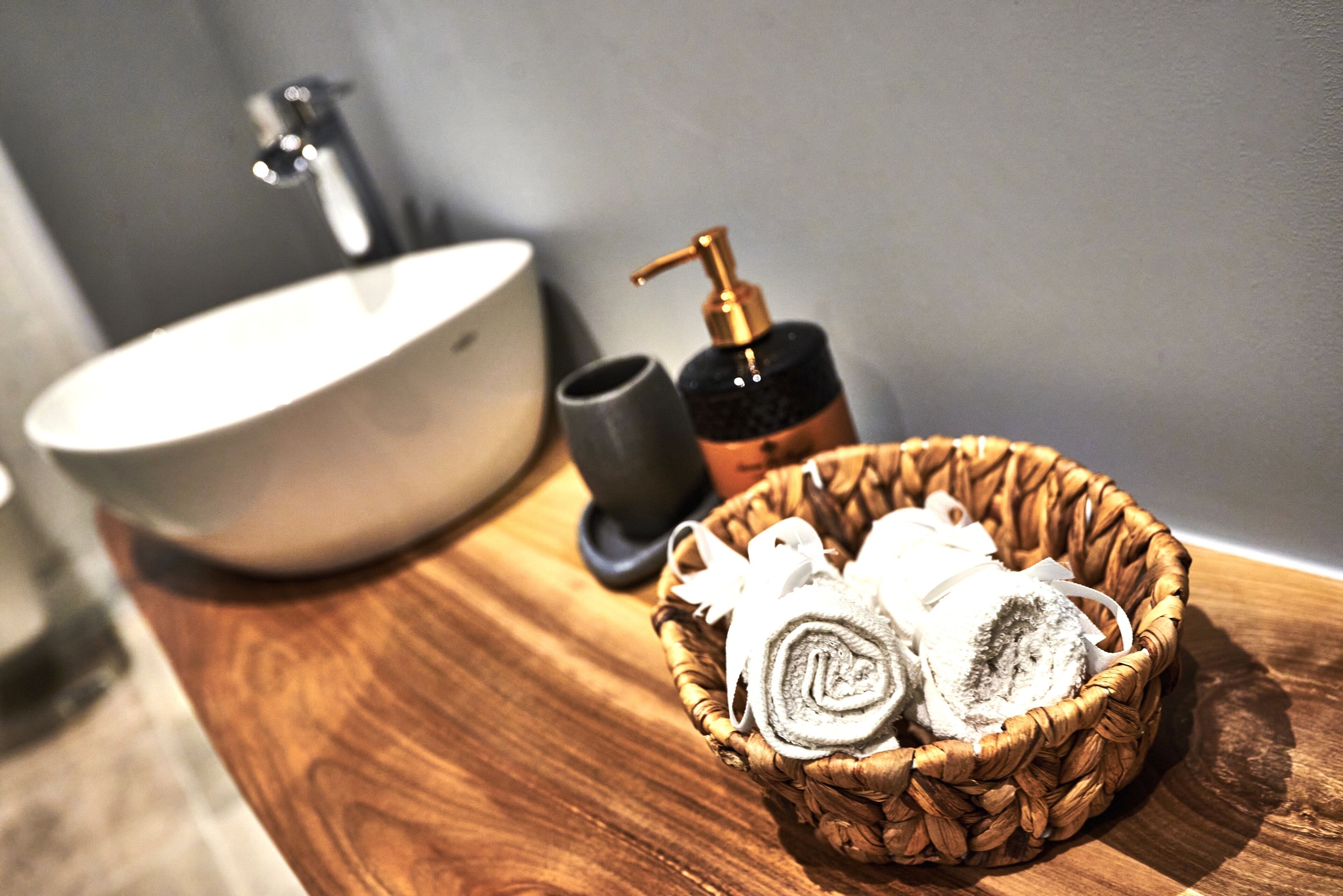Un lavabo, un distributeur de savon et un panier contenant des serviettes pliées.
