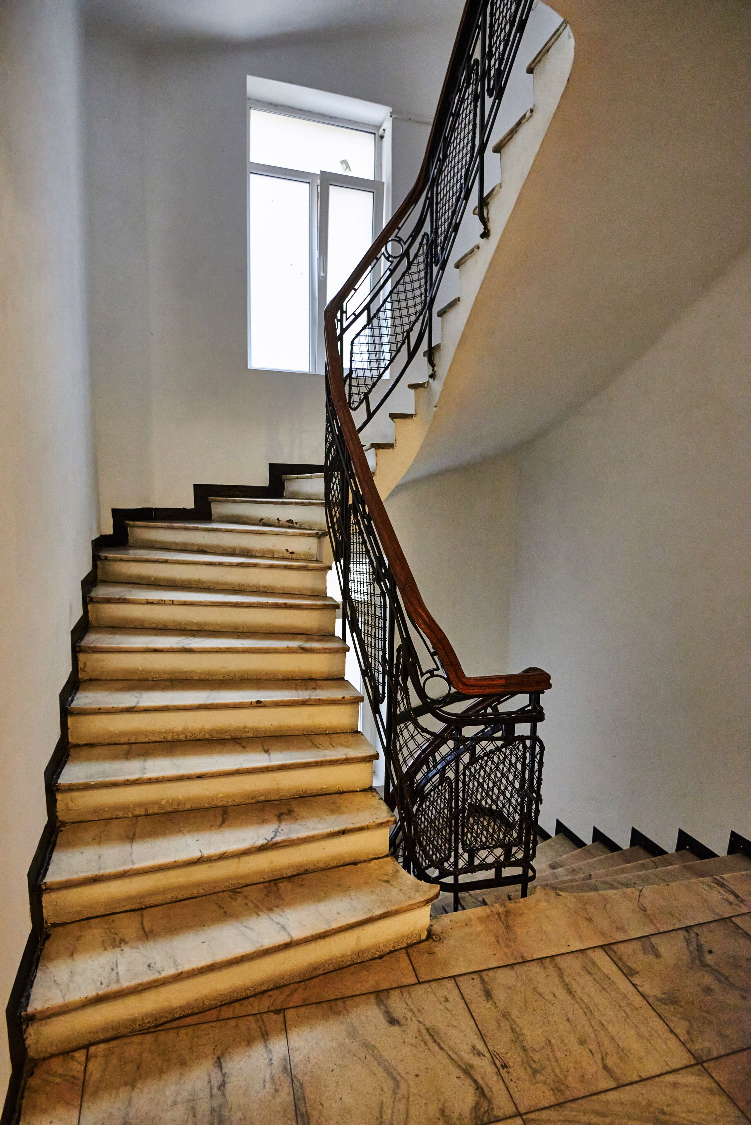 A staircase with a wooden handrail and metal balusters, leading to an upper floor.