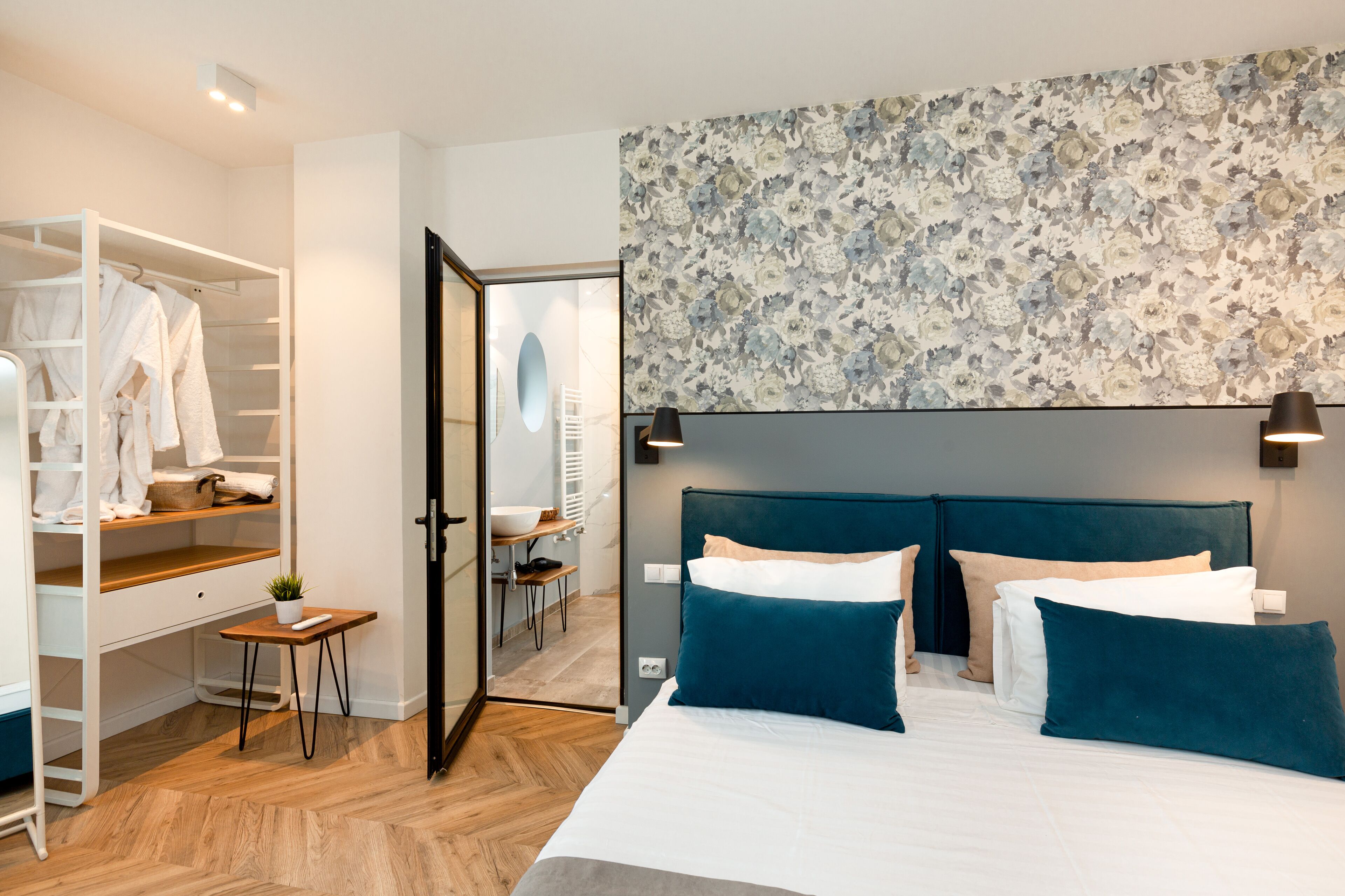 A bedroom with a bed, a wardrobe, a small table with a plant, and a desk with a chair.