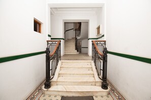 A staircase with a green stripe, black railings, and patterned floor tiles. - Metropole Apartments Royal Residence (Bucharest)