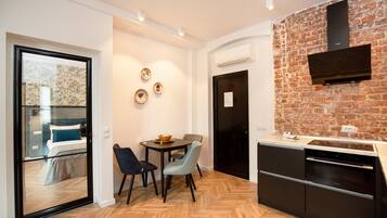 Una cocina moderna con pared de ladrillo, una zona de comedor con dos sillas y una mesa, y un lavavajillas negro.