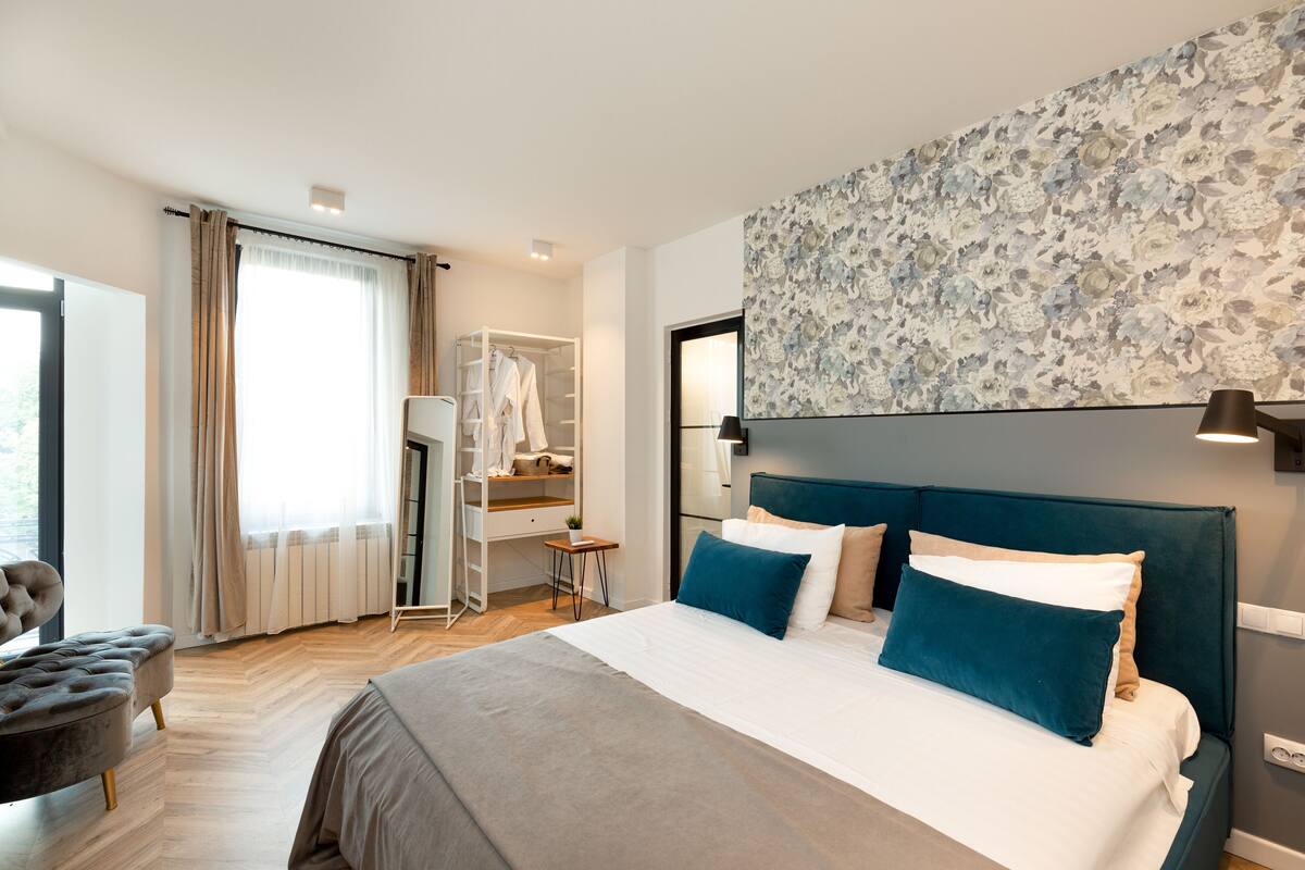A hotel room with a large bed, a wardrobe, a desk, and a chair.