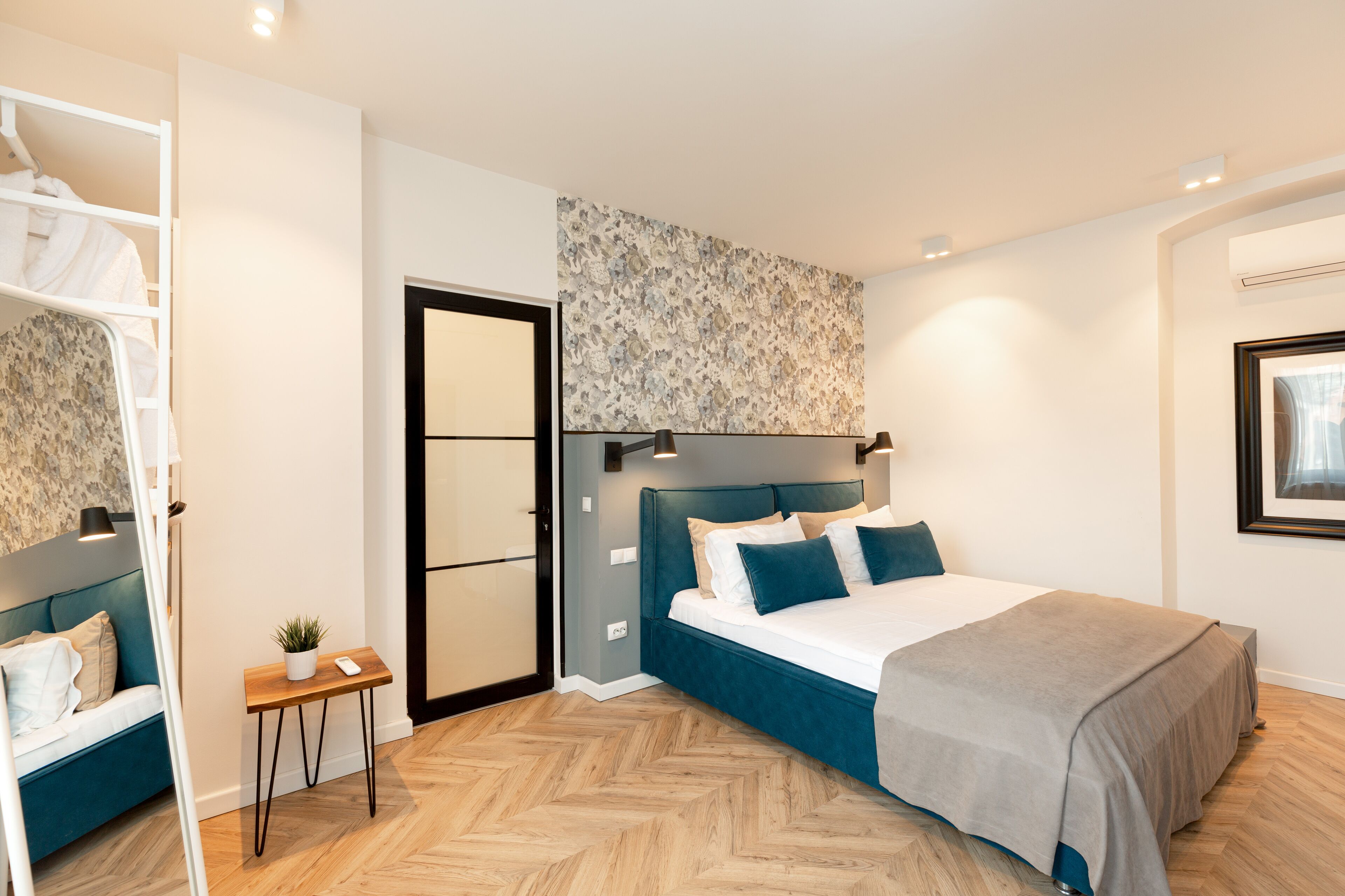 Une chambre moderne avec un lit, une petite table sur laquelle est posée une plante, et une armoire.