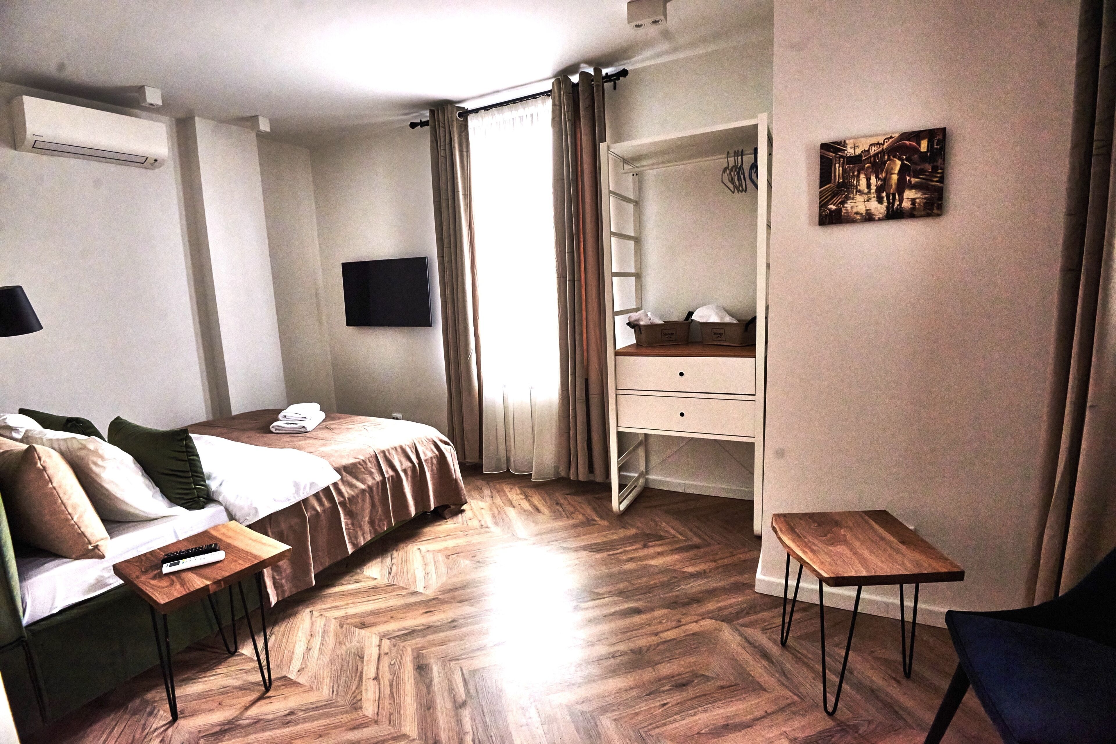 Ein Hotelzimmer mit Bett, Schreibtisch, Sessel, Fernseher und einem Bild an der Wand.