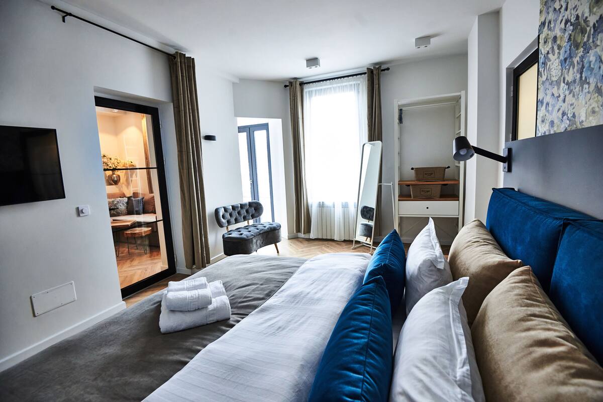 A modern hotel room with a large bed, a flat-screen TV, a desk, and a chair.