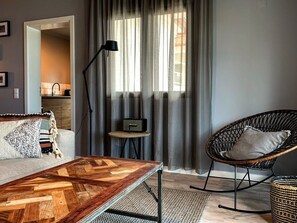 A modern living room with a wooden coffee table, a black rocking chair, and a small side table with a radio.