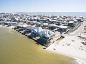 An aerial view of a coastal residential area with houses built on stilts over water, connected by walkways. - Corner pet-friendly, 5/3 bay sunset views! - TraMarLis (Dauphin Island)