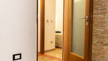 Un corridoio con una porta in legno che dà su una camera da letto con un letto e un comodino.
